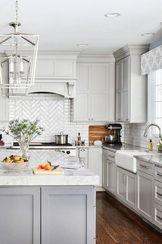 a kitchen with white cabinets and an island in the middle is decorated with silver accents