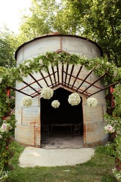 an outdoor wedding ceremony with flowers and greenery on the top of a round structure