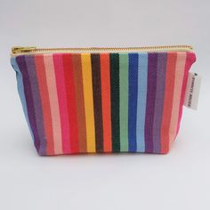 a multicolored striped zipper bag with a tag on the bottom that says,