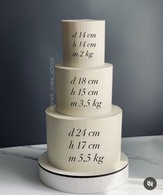 three tiered cake sitting on top of a white table next to a measuring tape