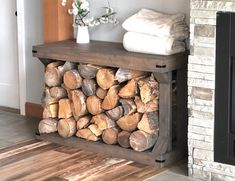 a stack of logs sitting on top of a wooden table next to a fireplace with towels