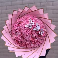 a woman holding a bouquet of pink roses and butterfly brooches in her hand