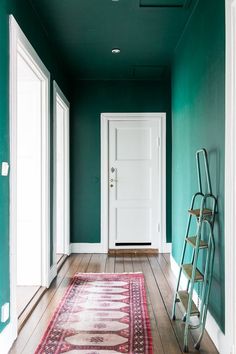 an empty hallway with green walls and wooden flooring is painted in teal tones