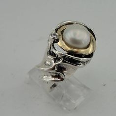 New ring band from my collection. The ring is made of 925 sterling silver with 8mm round freshwater White Pearl framed with 2mm wide 9K polished solid yellow gold. Also, the unique ring has tiny sparkling CZ that give it charming look. Must see! Labeled and stamped 925. This beauty will be sent to you a gift box. (All stains, if are any, are due to camera). This photos does not do justice to this superb piece! Please feel free to contact us in any matter... Material: Sterling Silver 925 , Yellow Anniversary Sterling Silver Pearl Ring In Yellow Gold, Yellow Gold Sterling Silver Pearl Ring For Anniversary, Sterling Silver Yellow Gold Pearl Ring For Anniversary, Sterling Silver Open Pearl Ring With Polished Finish, Elegant Dome Ring Stamped 925 For Anniversary, Elegant Dome Ring For Anniversary, Stamped 925, White Dome Ring With Polished Finish For Anniversary, Anniversary White Dome Ring With Polished Finish, Sterling Silver Pearl Ring With Polished Finish For Anniversary