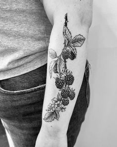 a woman's arm with berries and leaves on it