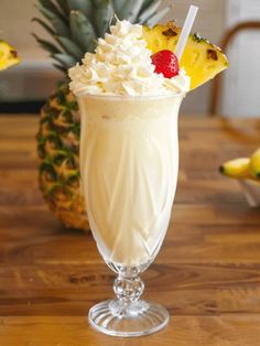 a pineapple drink is garnished with whipped cream