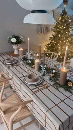 a dining room table set for christmas with candles and decorations on the table next to it