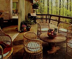 an outdoor patio with wicker furniture and potted plants on the table, surrounded by trees