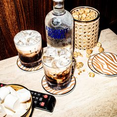 a table topped with drinks and desserts next to a bottle of alcohol on top of a table