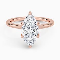 a rose gold ring with an oval cut diamond in the center and three clawed shoulders