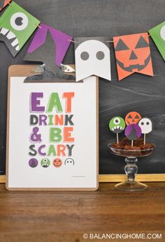 a halloween party with cupcakes and decorations on a table next to a chalkboard