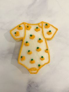 a cookie shaped like a baby's bodysuit with green and yellow icing