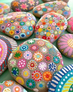 colorful painted rocks sitting on top of a green table covered in dots and flowers,