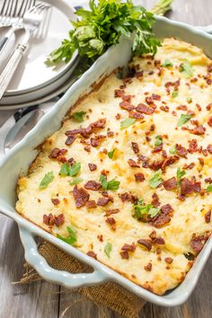 a casserole dish with bacon and parsley in it on a wooden table