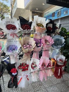 a bunch of flowers that are sitting on a rack in front of a building with the words i love you written on it