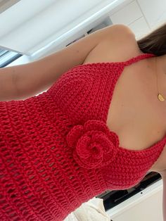 a woman taking a selfie in a mirror wearing a red sweater with a flower on it