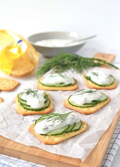 small crackers with cucumber and dill are on a wooden cutting board