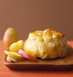 a piece of bread sitting on top of a wooden cutting board next to an apple