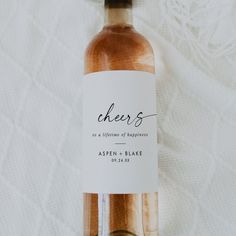 a bottle of wine sitting on top of a white cloth covered tablecloth with the words cheers printed on it