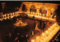 an outdoor wedding with candles lit up in the center and people standing around on either side