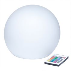 a remote control sitting next to a large white ball shaped light with buttons on it