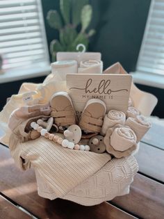 a basket filled with lots of baby items on top of a wooden table next to a potted plant