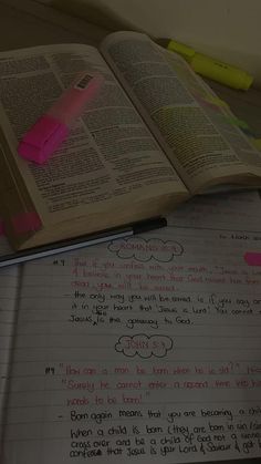 an open book sitting on top of a desk next to a pen and paper with writing