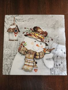 a paper napkin with a snowman and birdhouse on the front, which has been drawn by hand