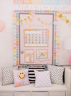 a white bench topped with lots of pillows next to a wall covered in stickers