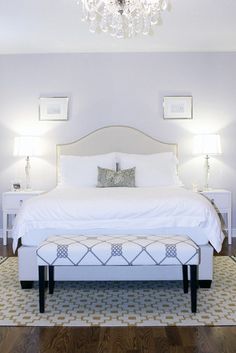 a white bed sitting in a bedroom next to two lamps