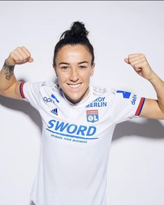 a female soccer player posing for a photo with her arms in the air and smiling