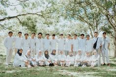 a group of people standing and sitting in front of some trees with headscarves on