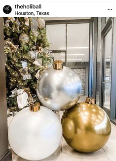 two white and gold ornaments sitting next to a christmas tree