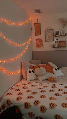 a bedroom decorated for halloween with pumpkins on the bed and lights strung over the headboard