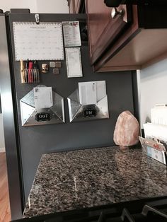 a granite counter top in a kitchen with magnets and calendars on the wall