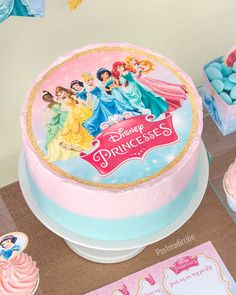 there is a cake with princesses on it and other items around it for decoration