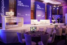 a large room filled with white chairs and tables covered in purple lighting next to tall windows