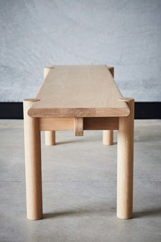 a small wooden table sitting on top of a cement floor next to a white wall