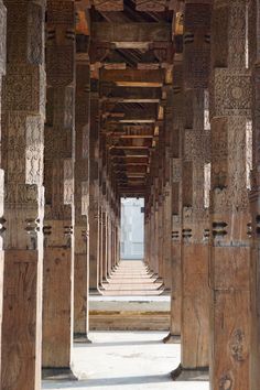 the inside of an old building with wooden columns and carvings on the walls, all lined up in rows