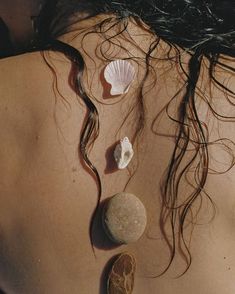 the back of a woman's neck with seashells and rocks on it