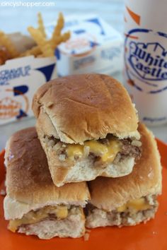 two sandwiches stacked on top of each other on an orange plate next to french fries