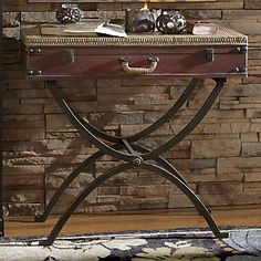 an old suitcase is sitting on a table in front of a brick wall and lamp