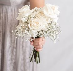 a woman holding a bouquet of white flowers