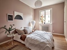 a bed sitting in a bedroom next to a window with a lamp on top of it