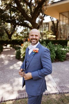 a man in a blue suit and flower boutonniere smiles at the camera