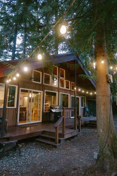 a small cabin with lights hanging from the roof and stairs leading up to it's deck