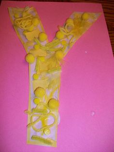 the letter y is made out of yellow flowers and plastic wrappers on pink paper