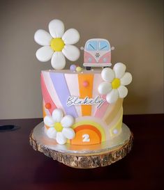 a birthday cake decorated with flowers and a camper on the top is sitting on a table