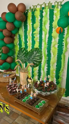 a table topped with lots of cupcakes and cake covered in green frosting