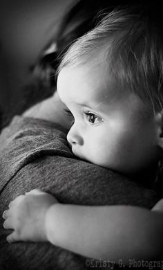 a black and white photo of a baby holding it's mother in her arms